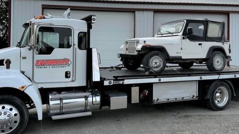 White Jeep on White flatbed tow truck